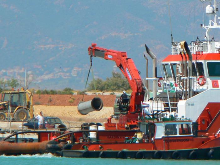 Rimorchiatore che carica tubi dal cantiere.